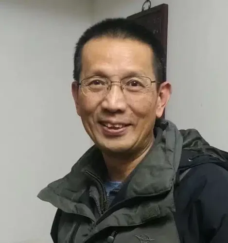 Kiinalainen mies katsoo hymyillen kohti kameraa