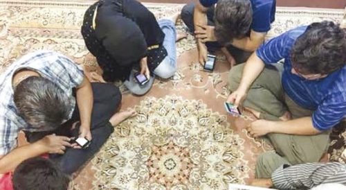 Ihmisiä istuu lattialla tutkimassa puhelimiaan.